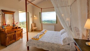 A bedroom with a four-poster bed, a wooden dresser, a chair, and a view of the landscape. - Villa 'Corali Ideales Resort' with Sea View, Wi-Fi and Air Conditioning (kefalonia)
