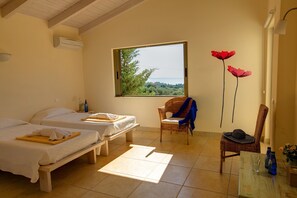 A room with two beds, a window with a view, a chair, and a table with bottles.