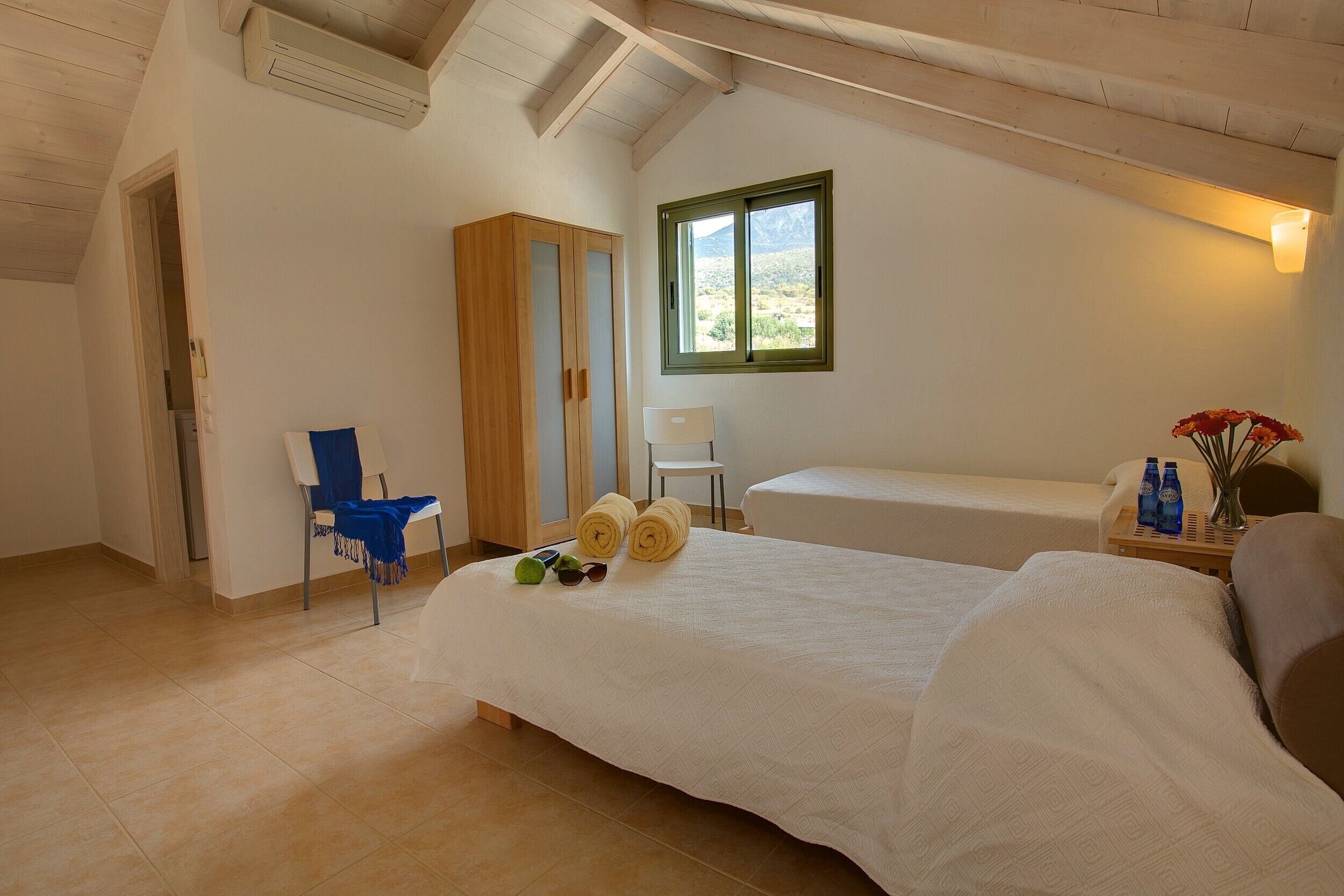 A bedroom with a bed, a chair, a wardrobe, and a window with a view.