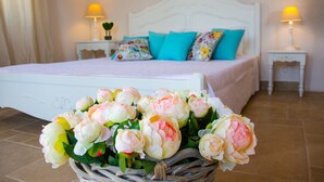 Un dormitorio con cama, almohadas, una mesita de noche, una lámpara y un cesto de flores.