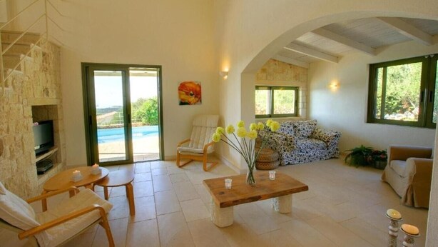 Amplia sala de estar con chimenea de piedra, televisor, sofá y vista a una piscina.