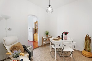 Uma área de refeições com uma mesa branca, cadeiras e um lustre.