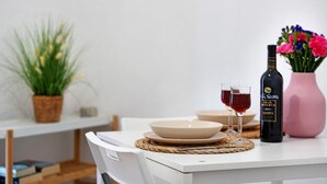 Une table à manger avec une bouteille de vin, un vase de fleurs et un verre de vin rouge.