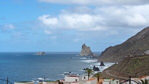 Une vue sur la côte, avec des formations rocheuses, un ciel dégagé et des bâtiments le long du littoral.