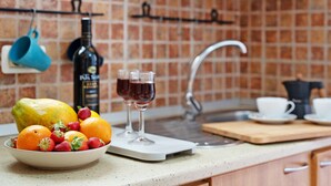 Une cuisine avec un saladier de fruits, une bouteille de vin et des verres.