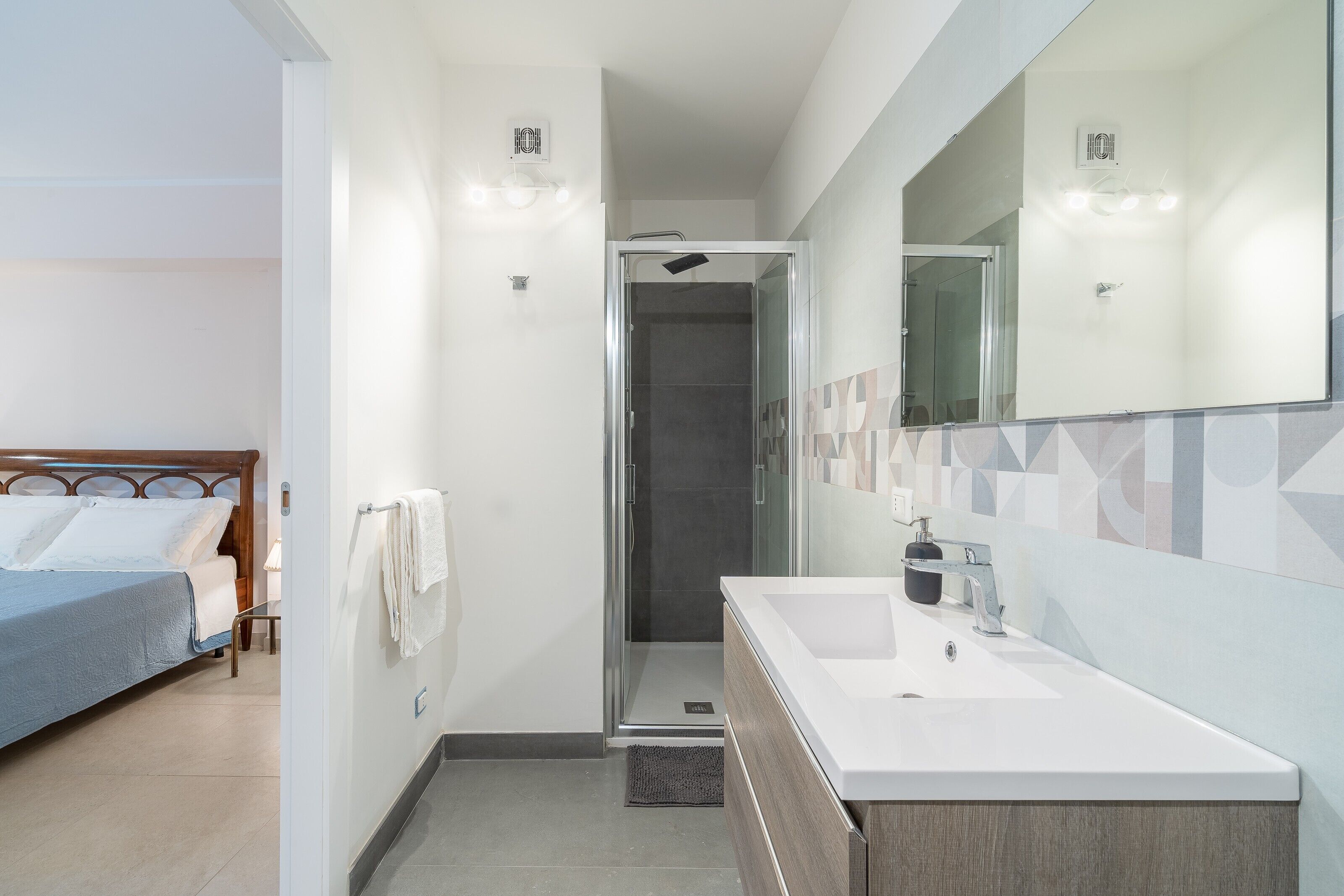 A modern bathroom with a shower, a sink, and a mirror.