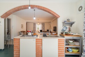 Une cuisine avec une arche en briques, une cuisinière à gaz, un évier et un coin repas comprenant une chaise et une table.