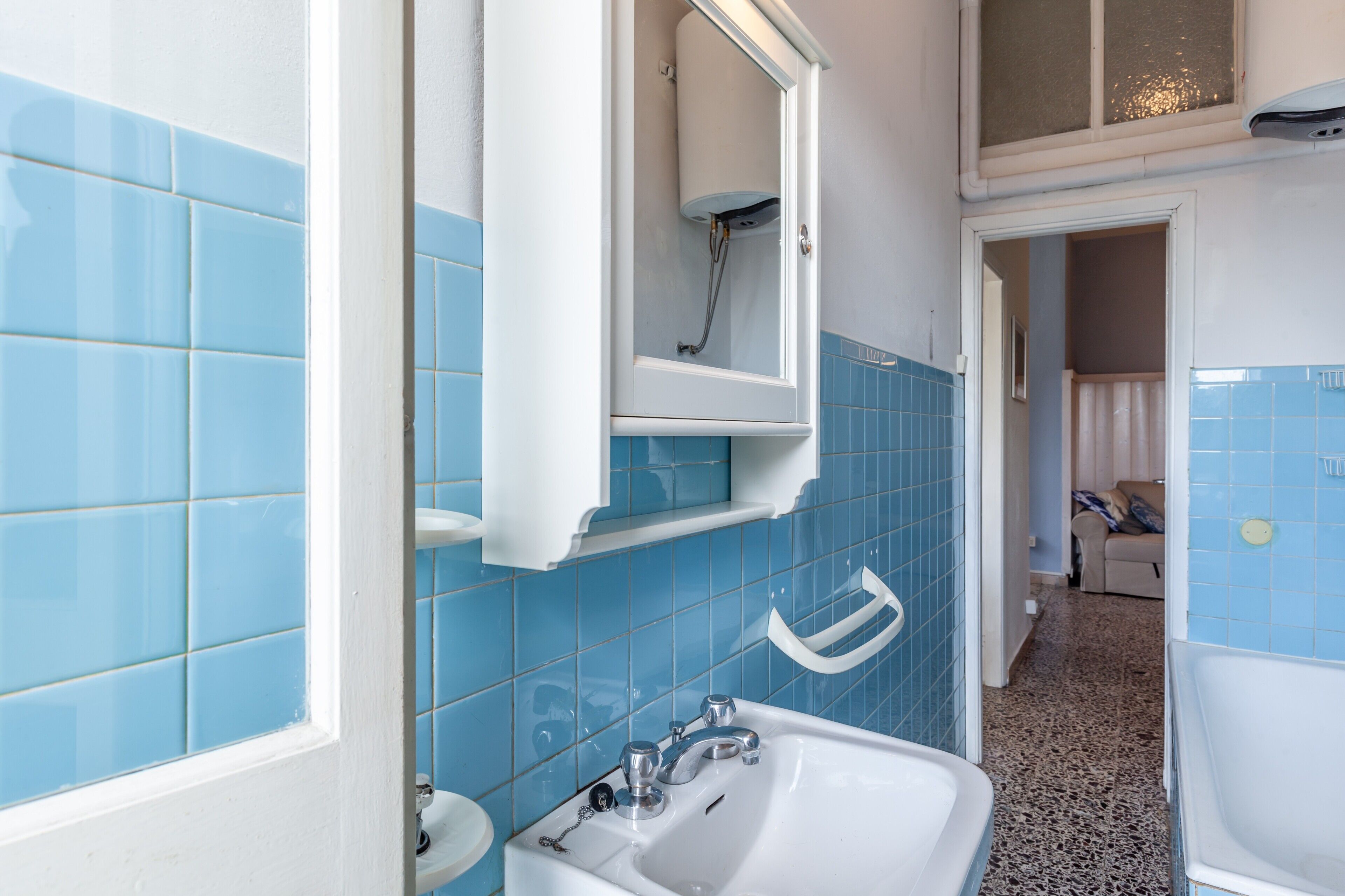 A bathroom with blue tiles, a white sink, and a shower.