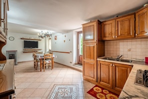 Une cuisine avec des meubles de rangement en bois, une cuisinière encastrée et un coin repas comprenant une table et des chaises.