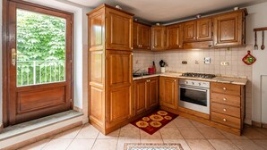 Eine Küche mit Holzausstattung, einem Gasherd, einem Backofen und einem Fenster mit Blick auf Grünflächen.