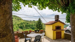 Eine Terrasse mit Tisch und Stühlen, einem kleinen Backofen aus Ziegeln und Kübelpflanzen.