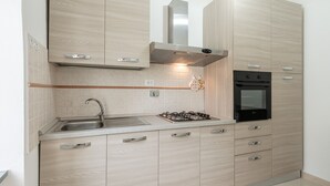 Une cuisine moderne avec des meubles en bois clair, des appareils en acier inoxydable et un four encastré.