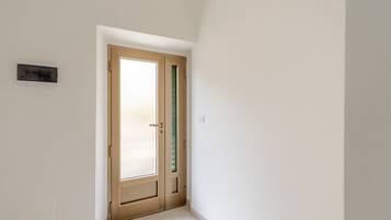 Un corridoio stretto con una porta in legno, un interruttore della luce e un piccolo dispositivo a parete.