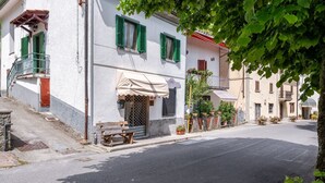 Une rue bordée d’immeubles, avec un banc et des plantes en pot.