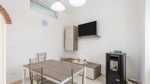 Une cuisine moderne avec une table à manger, des chaises, un téléviseur fixé au mur et une cuisinière intégrée.