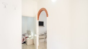 Une chambre avec un lit, une table de chevet, une lampe et un téléviseur fixé au mur.