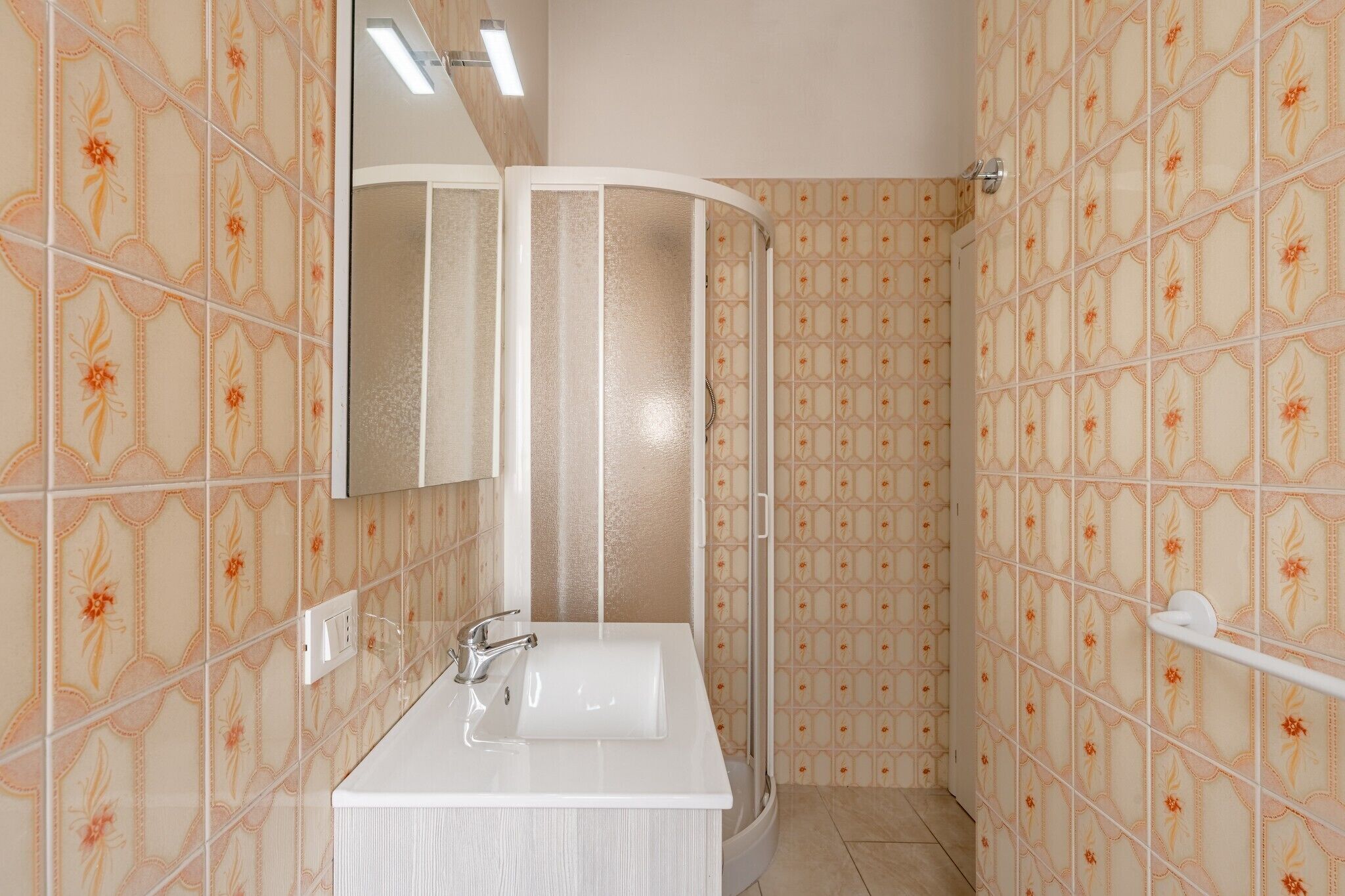 Ein Badezimmer mit Dusche, Waschbecken und Spiegel.