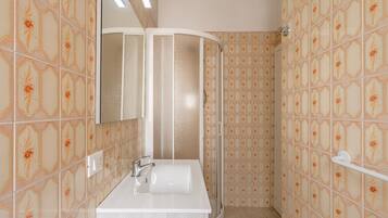 Ein Badezimmer mit Dusche, Waschbecken und Spiegel.
