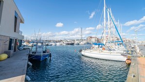 A marina with boats docked, a wooden pier, and a building with a balcony. - Apartment 'Résidence La Croisette' with Sea View and Private Terrace (Agde)