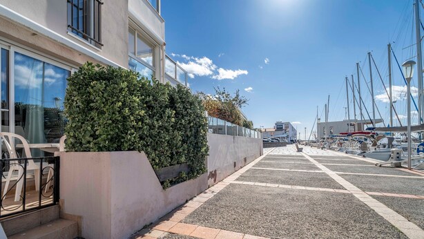 A marina with boats, a building with large windows, and a paved walkway. - Apartment 'Résidence La Croisette' with Sea View and Private Terrace (Agde)