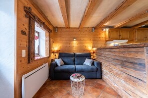 Interno di una baita di legno con un divano, un tavolino e pareti in legno.