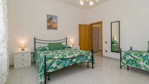 Une chambre à coucher comprenant un lit, des tables de chevet, un miroir, une porte et un luminaire au plafond.