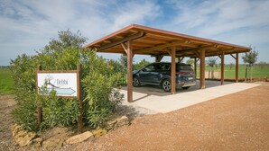 Un espace de stationnement couvert avec une voiture, un panneau de signalisation et de la végétation environnante.