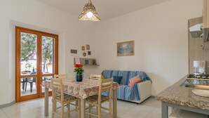 Un espace repas comprenant une table, des chaises, un vase avec des fleurs, un canapé et un comptoir de cuisine.