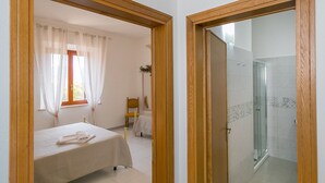 Un dormitorio con cama, una silla y un ventanal con cortinas.
