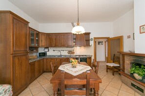 Una cucina con mobili in legno, un tavolo da pranzo con sedie, un lampadario e un camino.