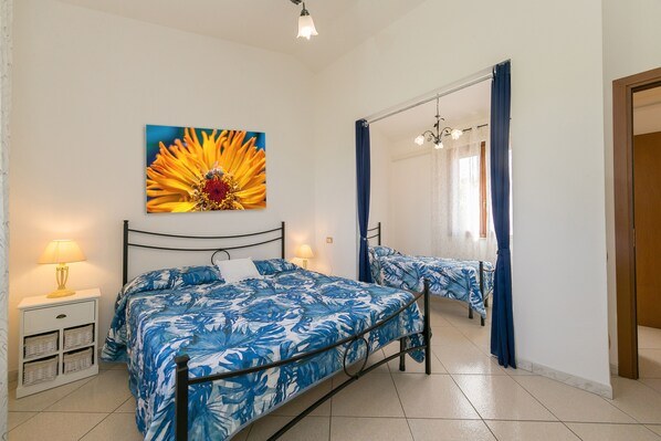 Ein Schlafzimmer mit einem Bett, einem Nachttisch, einer Lampe, einem Spiegel und einem großen Blumenbild an der Wand.