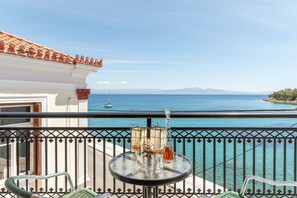 A balcony with a table, chairs, and a view of the sea.
