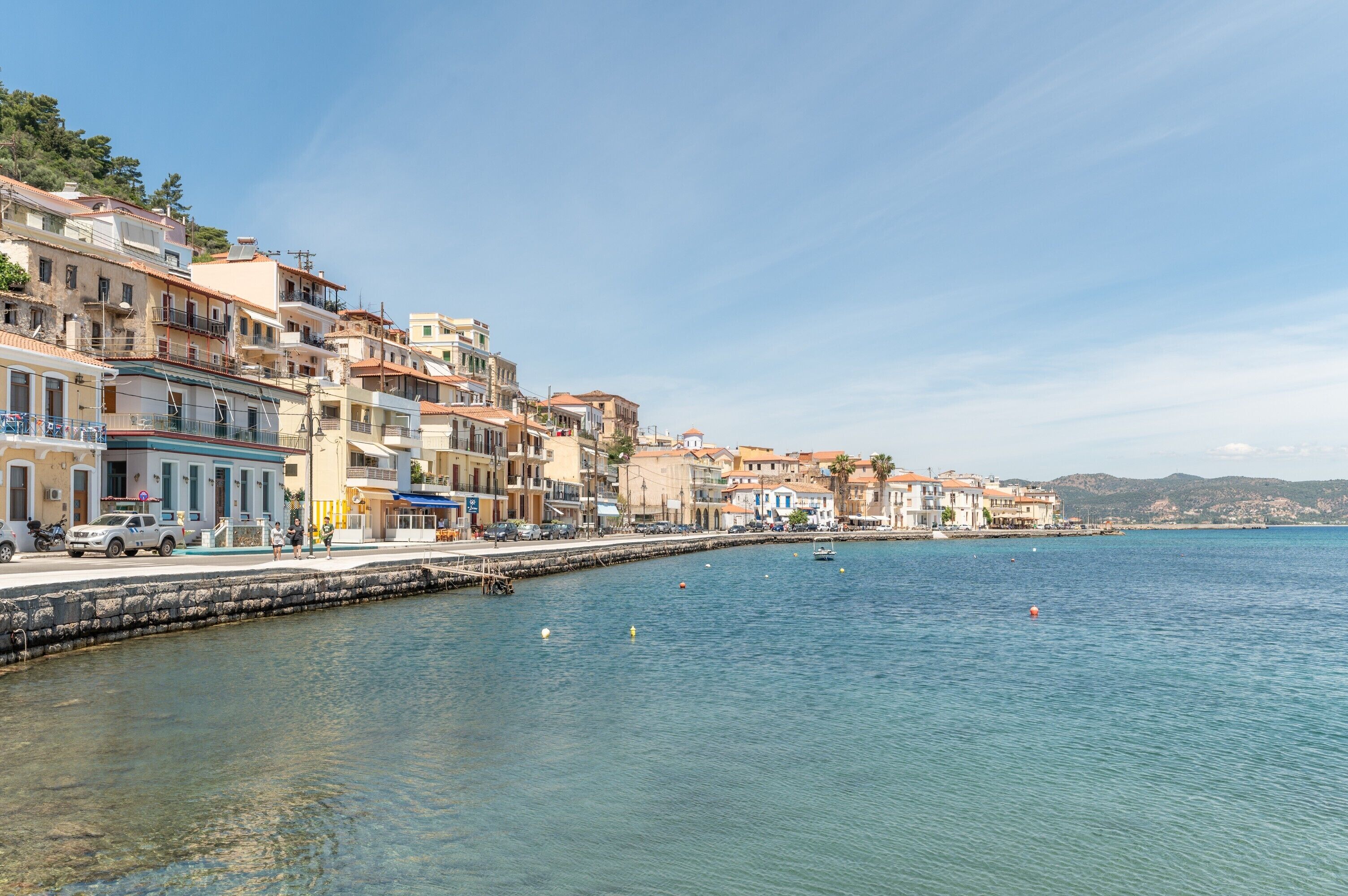 A coastal town with buildings along the waterfront, a pier, and clear blue water.