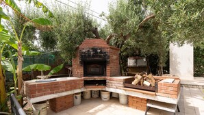 An outdoor brick oven with a fire pit, surrounded by trees and potted plants. - Villa Margi with Sea View, Shared Pool, Private Terraces and Wi-Fi (Scopello)