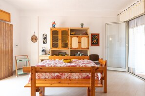Una habitación con una cama de madera, un armario de madera con puertas de cristal, una mesita y una silla.
