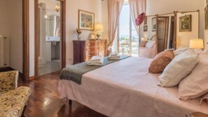 Un dormitorio con cama, cómoda, silla y vistas al balcón.