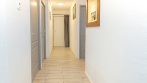 A narrow hallway with wooden flooring, white walls, and doors leading to rooms.