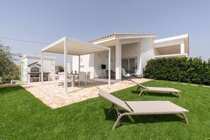 A modern house with a patio, outdoor seating, and a well-maintained lawn.