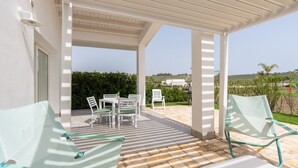 A covered outdoor seating area with chairs and a table, a pergola overhead, and a view of the landscape. - Holiday Home 'Villa Gioberta, Fiori' with Shared Pool, Wi-Fi and Air Conditioning (Menfi)