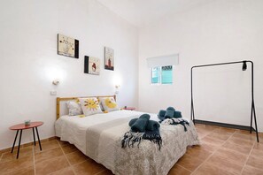 Un dormitorio con cama, una mesita, una lámpara de pie y una obra de arte en la pared.
