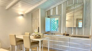 Una cocina moderna con una isla central, muebles blancos y un ventanal con vistas.