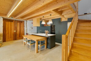 Una cocina moderna con vigas de madera, un comedor y una escalera.