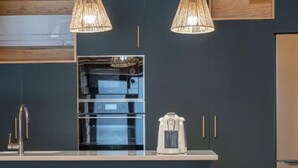 Una cocina moderna con armarios de madera, una isla central con lavamanos y dos lámparas colgantes.