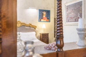 A bedroom with a wooden bed frame, a nightstand with a lamp, and two framed artworks on the wall.