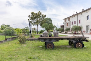 A flatbed trailer with potted plants in a grassy area with a building in the background.