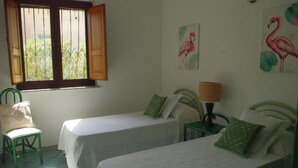 A room with two single beds, a chair, a window with open shutters, and wall art of flamingos. - Villa 'Maria' with Sea View, Private Terrace and Wi-Fi (Cala Liberotto)