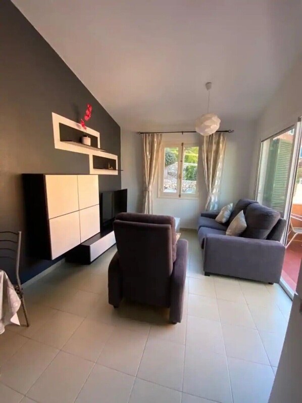 A modern living room with a sofa, TV, and a chair.