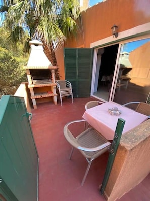 An outdoor patio with a grill, chairs, and a table.