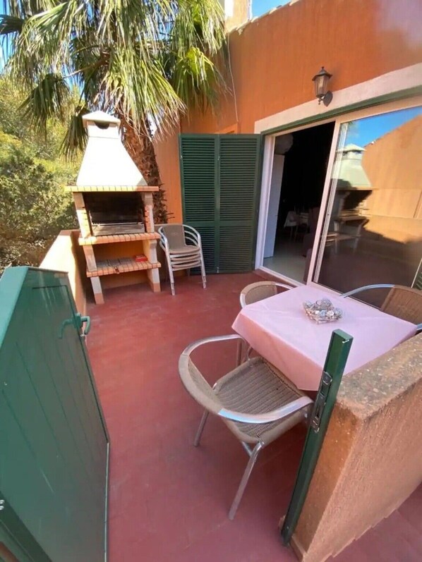 Une terrasse extérieure équipée d’un barbecue, de chaises et d’une table.