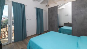 A bedroom with a skylight, a balcony, and a bed with a teal bedspread.